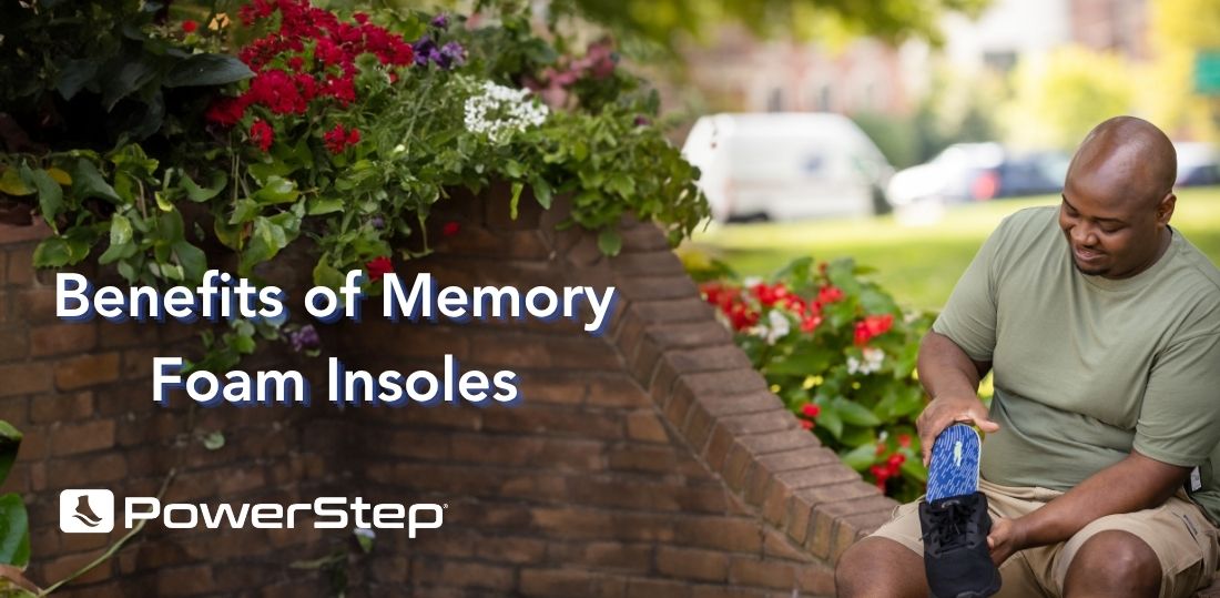 Man sitting on a brick wall, putting a memory foam insole into his shoe