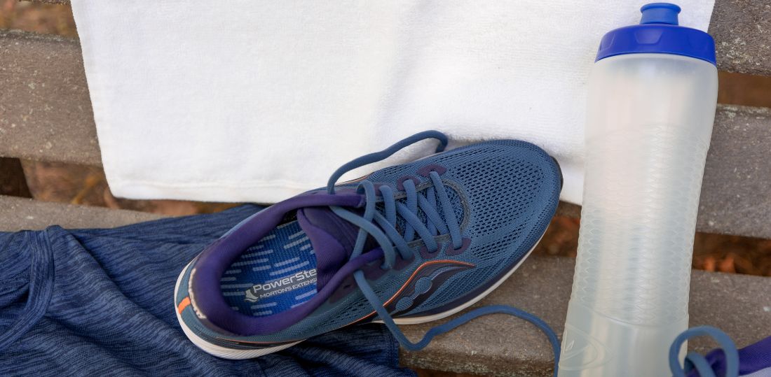 Shoe with Morton's Extension insole on a bench with a water bottle and towel