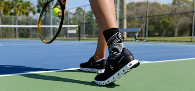 Woman playing tennis while wearing PowerStep Dynamic Ankle Support Sock