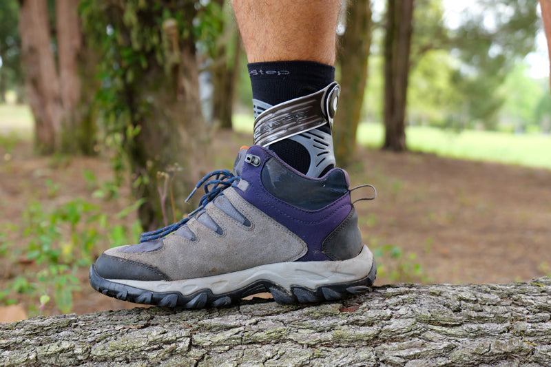 Man going on hike and stepping on log while wearing PowerStep Dynamic Ankle Support Sock