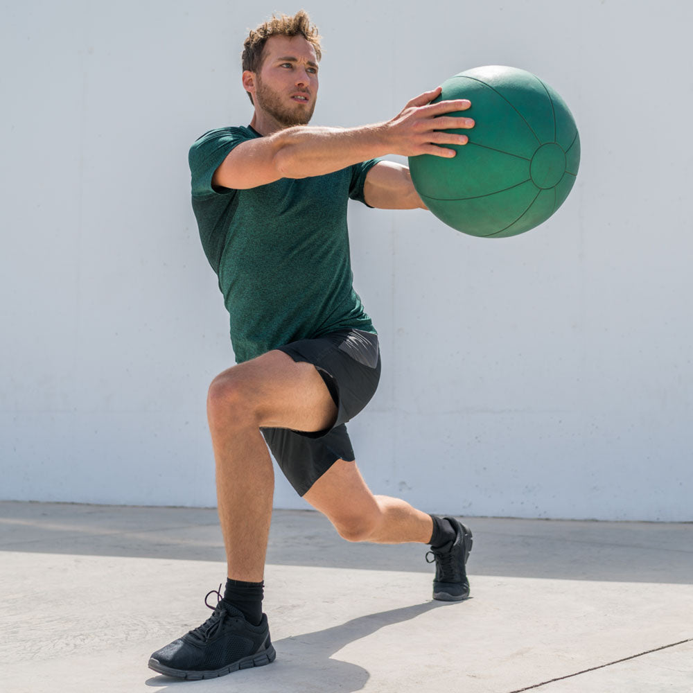 Man outside doing stretches while holding exercise ball