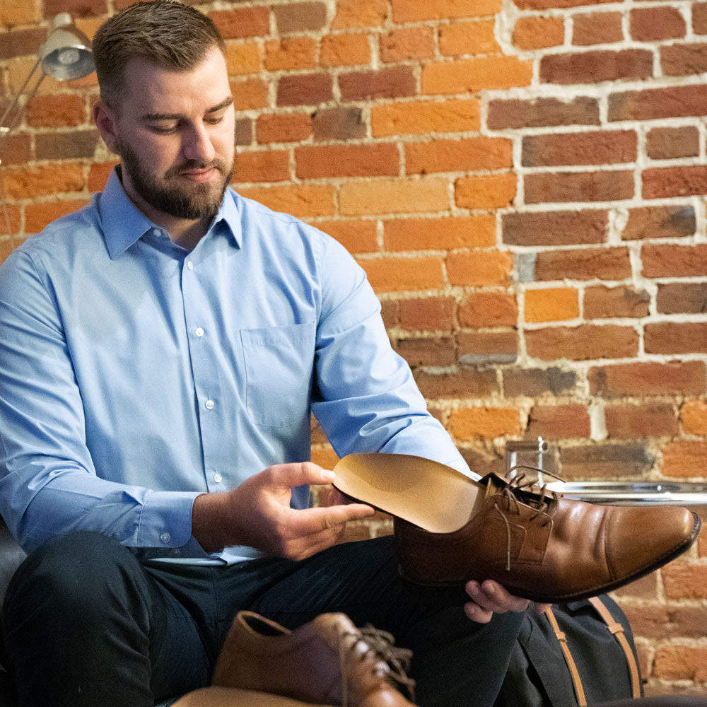 Man placing Pinnacle Dress full length insoles into brown leather dress shoe