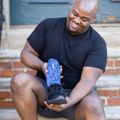 Man placing Pinnacle Low insole into black shoe while sitting on brick stairs