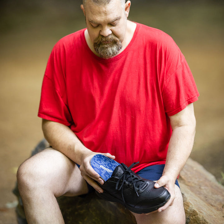 Man placing Pinnacle Wide Fit full length insoles into black sneaker