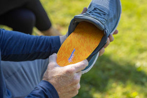 Man placing PowerStep PULSE orthotic insoles into sneaker