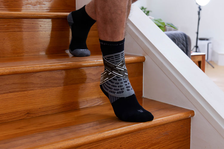 Man walking down stairs while wearing the PowerStep Dynamic Ankle Support Sock.