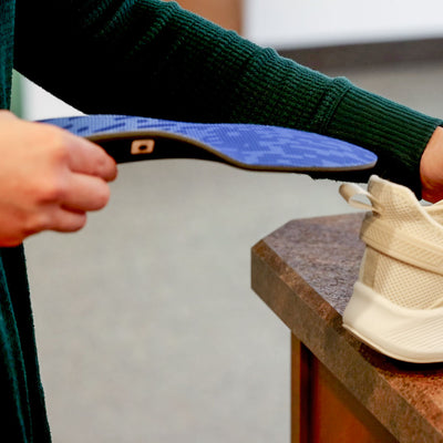 Person placing PowerStep Heat Moldable Insoles into tan sneaker