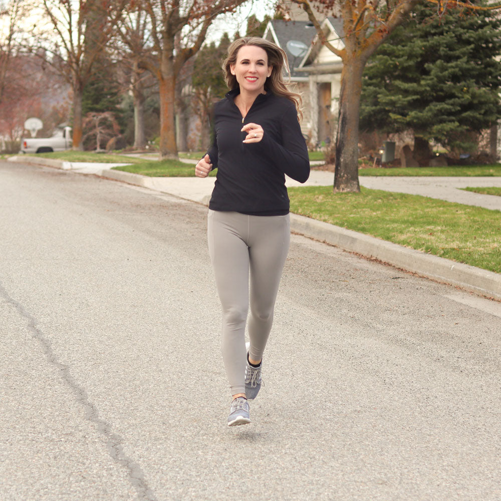 Woman jogging down suburban street while wearing PowerStep PULSE Thin 3/4 Insoles in her gray running shoes