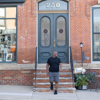 Man walking out of brick building while wearing black tennis shoes with PowerStep Pinnacle 3/4 insoles inside