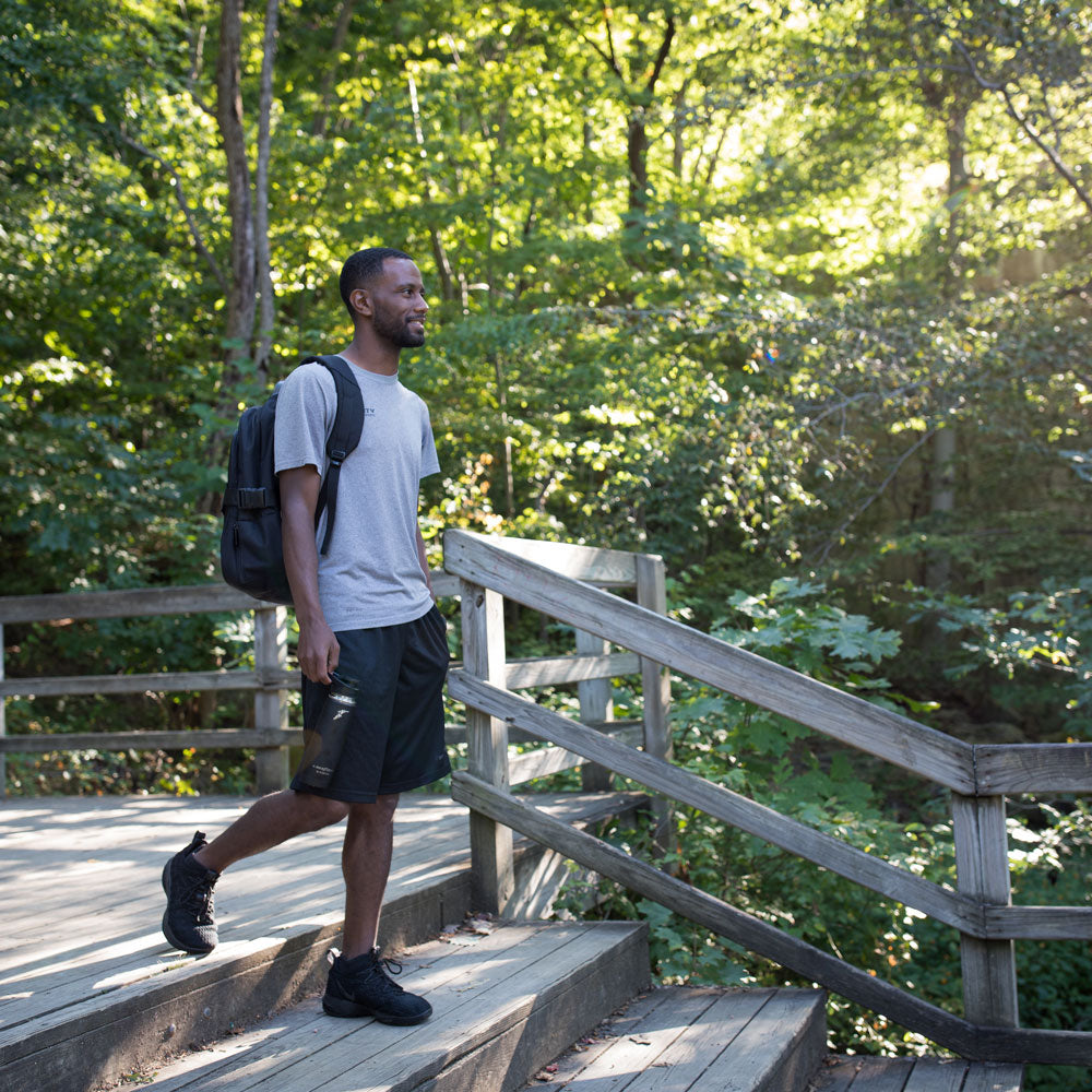 Man wearing backpack and holding thermos, ready to go hiking while wearing PowerStep Pinnacle Hiker insoles