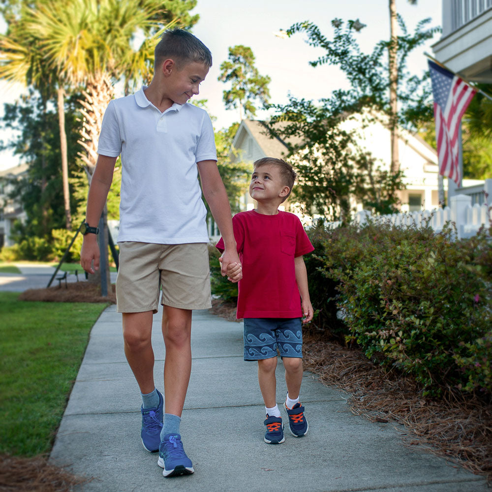 Two little boys walking down sidewalk