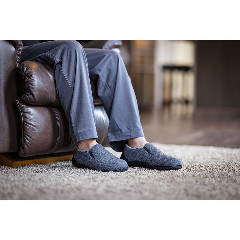 PowerStep Orthotic Arch Supporting slippers for Men, man sitting on couch while wearing orthotic arch supporting slippers, charcoal and light gray #color_charcoal