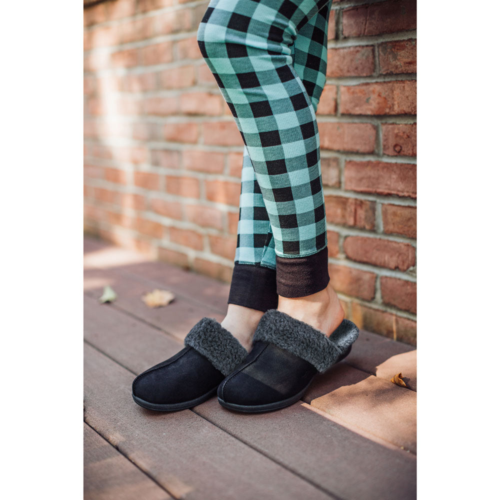 PowerStep Orthotic Arch Supporting slippers for Women, woman standing against brick wall on deck outside of home while wearing pajamas and black and charcoal slippers with arch support #color_black-charcoal
